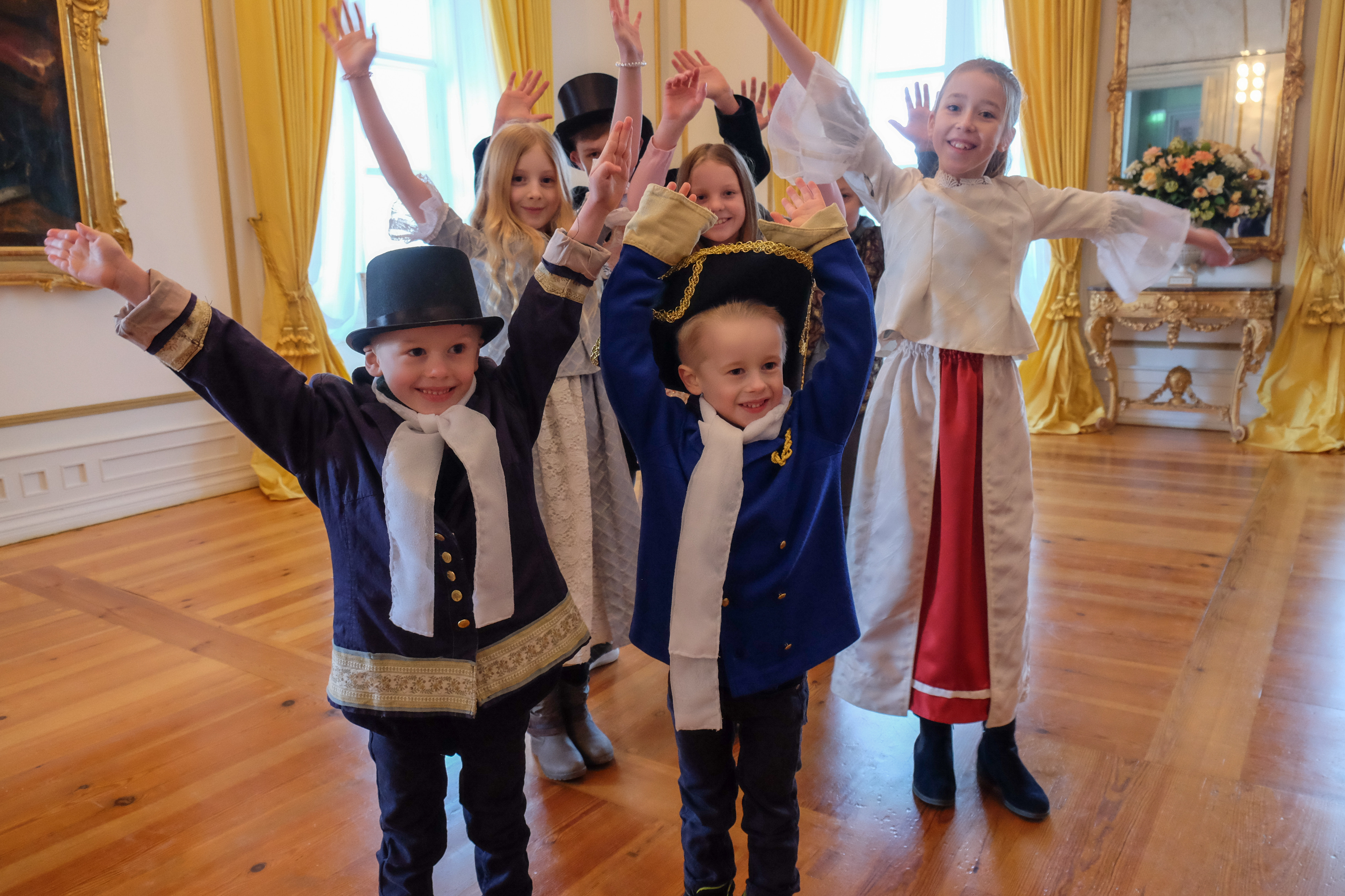 6 Kinder in altertürmlicher Schlosskleidung im einem zimmer mit gelben Vorhängen im Schloss Eutin.