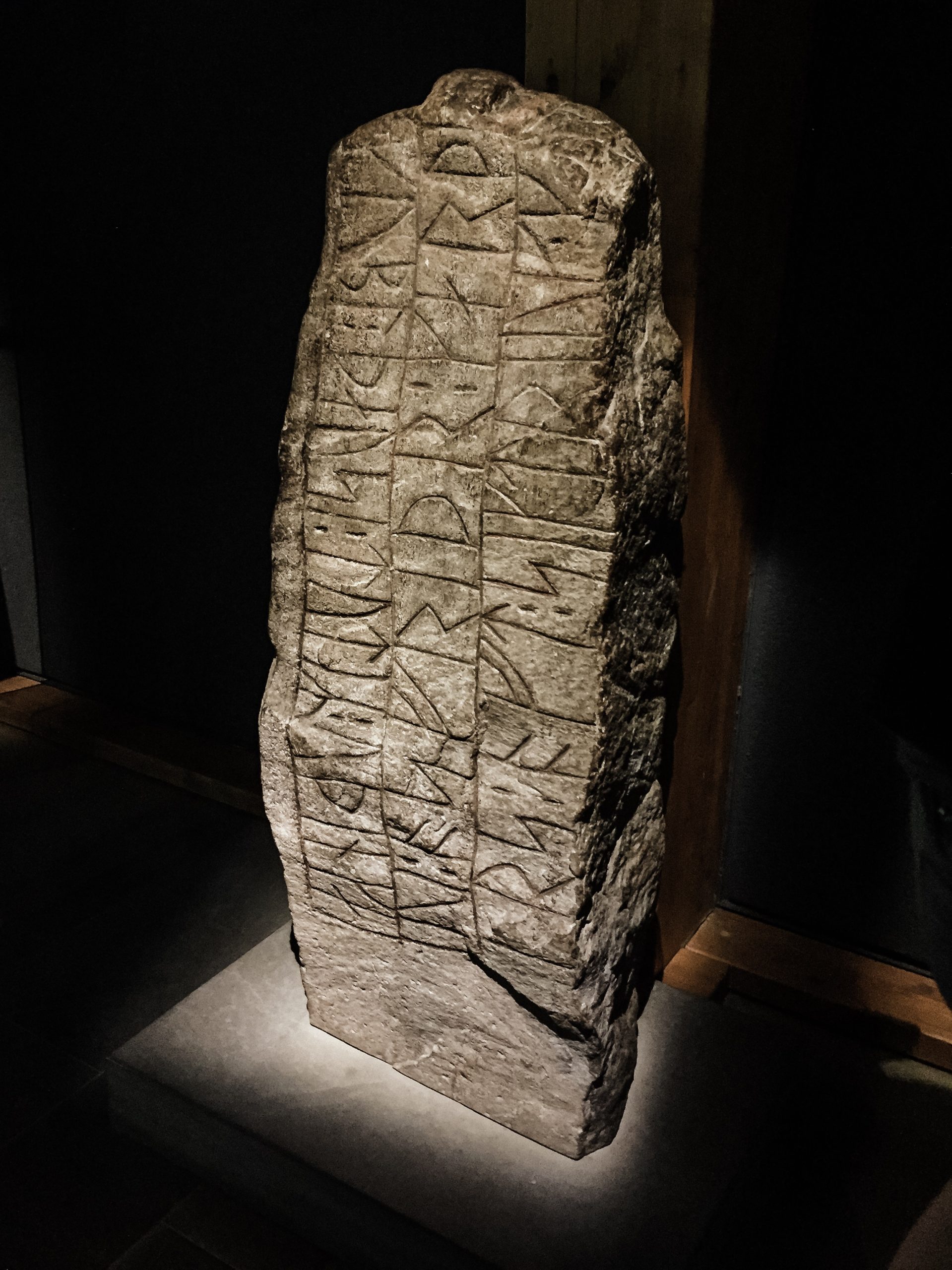Ein länglicher grauer Stein. Es ist der Runenstein im Museums in Haithabu.